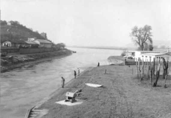 Der Beginn des Donaukanals in Nussdorf, schwarz/weiß fotografiert. Links und rechts Land, mittig verläuft der Donaukanal schräg. Einige Häuser und Bäume sind zu sehen.