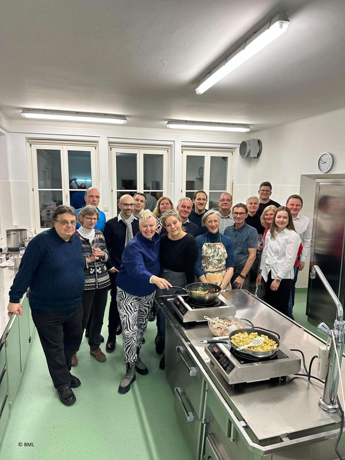 Gruppenbild der Sektion Wasserwirtschaft in der Küche im Kursgebäude des Institutes für Gewässerökologie und Fischereiwirtschaft. Man sieht die Pfannen mit dem Fischcurry im Vordergrund. 